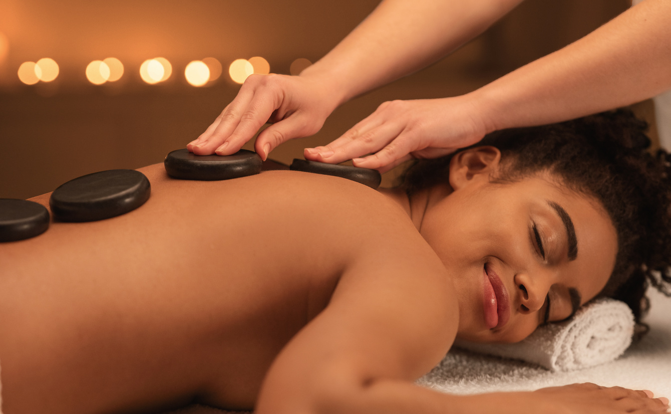 Healing hot stone massage for joyful black woman